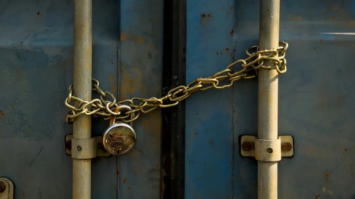 Close-up of blue container door bars secured with a chain and padlock