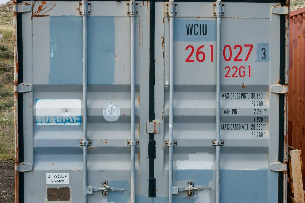 Doors of a used blue shipping container showing scuffs, dents and original markings