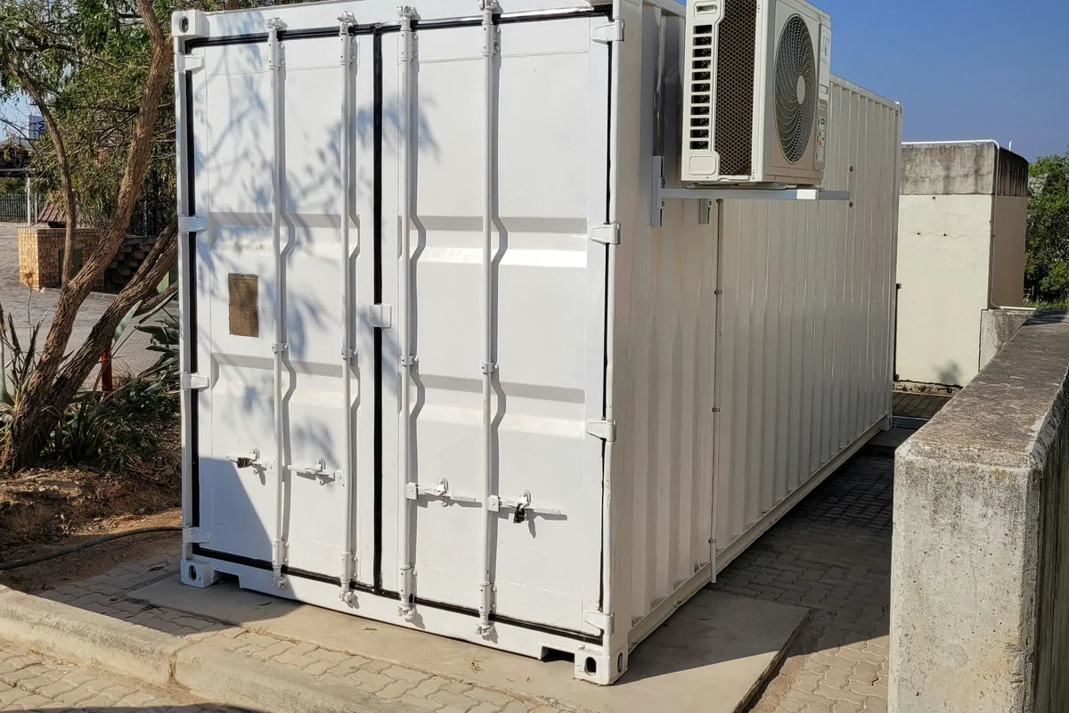 Clean white steel container with closed cargo doors, set on a paved pad in sunlight